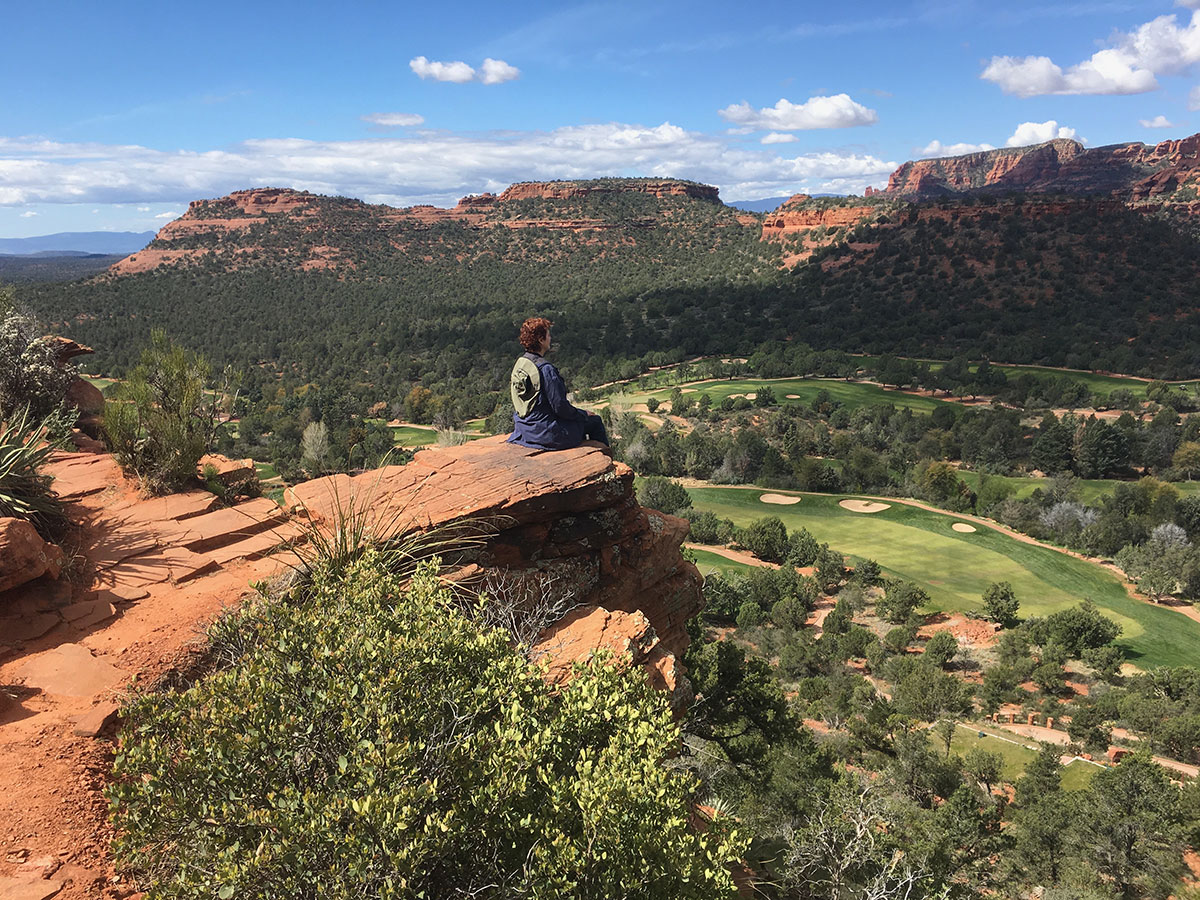 Woman sitting on a boulder looking over a canyon.